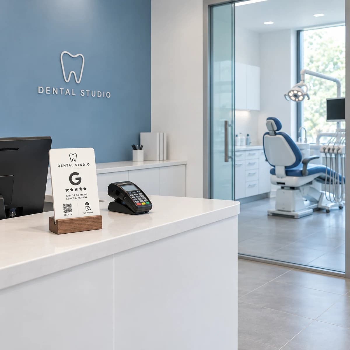 White Google review stand on a dental reception counter, with a blue treatment chair visible beyond