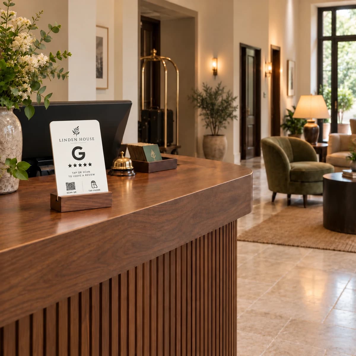White Google review stand on a walnut hotel reception desk, with lounge seating in the lobby behind it