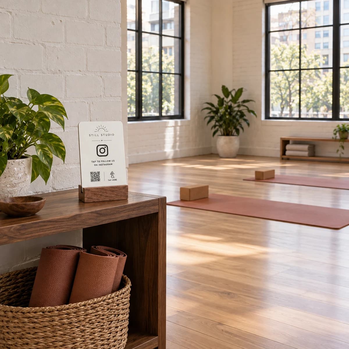 White Instagram stand on a wooden entry shelf in a yoga studio, with mats on the floor